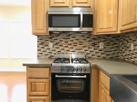 A kitchen with a stove, oven, microwave, and cabinets.