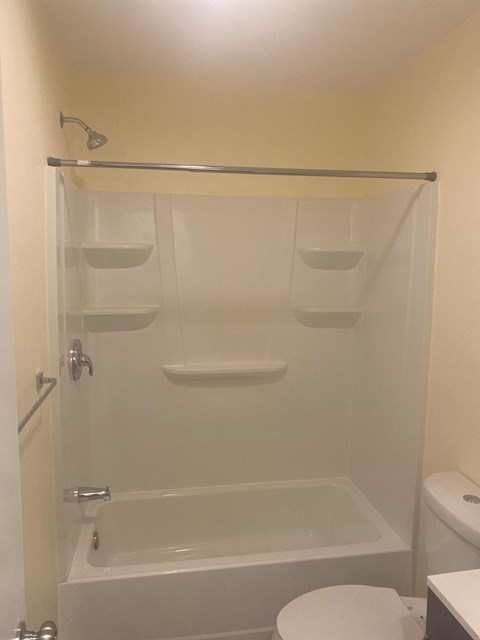 A white toilet is in a small bathroom with a walk-in shower.