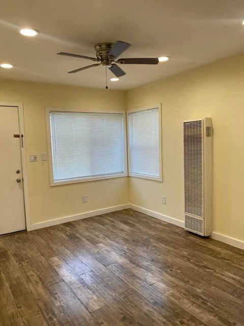 A room with a ceiling fan and a window with blinds.