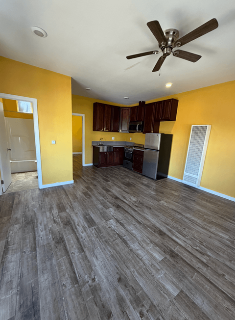 A room with a ceiling fan and wooden flooring.