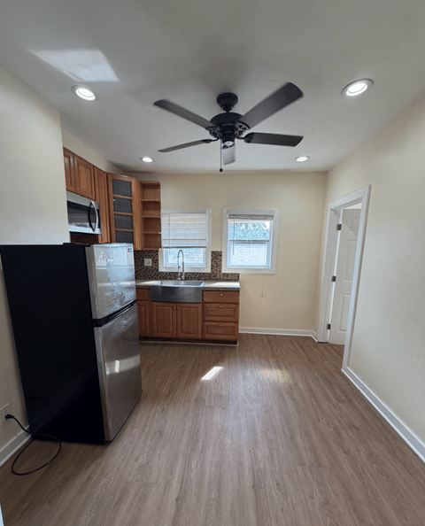 A kitchen with a black fridge and wooden cabinets.
