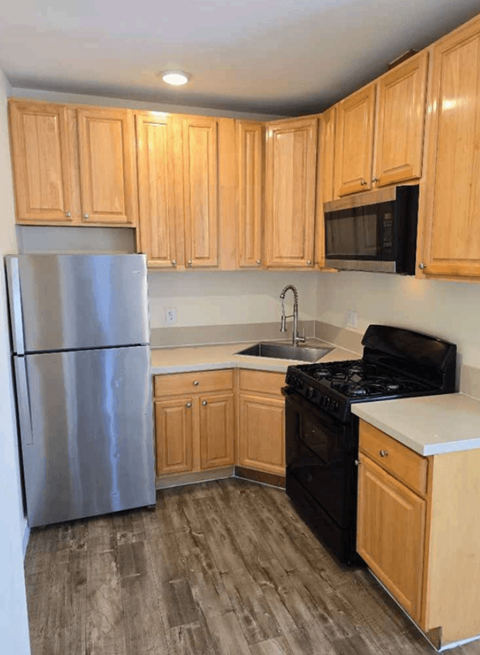 A kitchen with wooden cabinets and a stainless steel refrigerator.