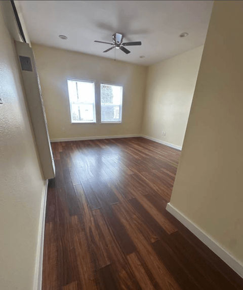 A room with a ceiling fan and wood flooring.