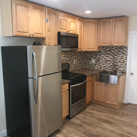 A kitchen with a stainless steel refrigerator and wooden cabinets.