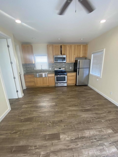 A kitchen with wooden cabinets and a black fridge.