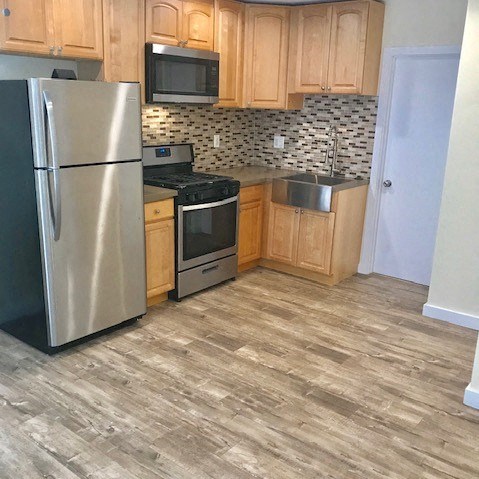 A kitchen with a stainless steel refrigerator, microwave, oven, and sink.