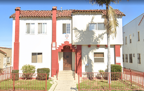 A red and white building with a palm tree in front.