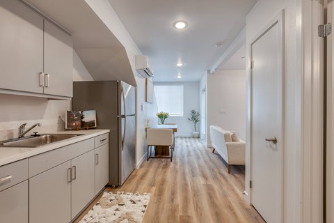 A modern kitchen with white cabinets and a wooden floor.