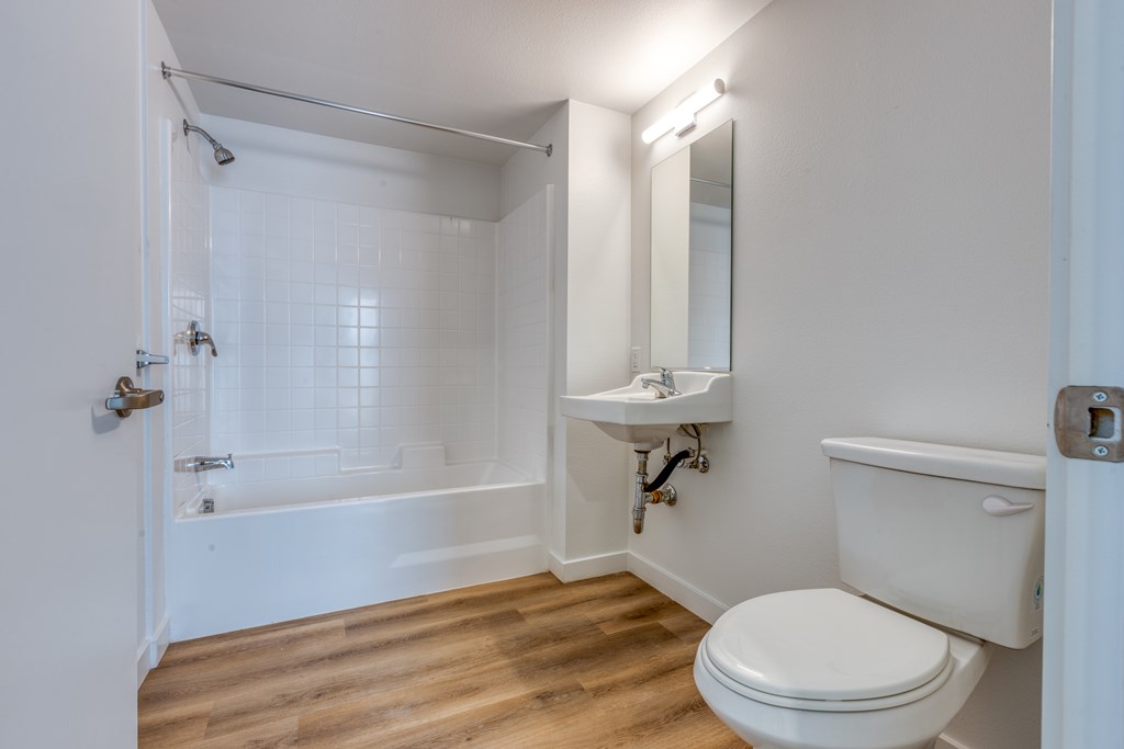 White bathrooms with a toilet, sink, and bathtub.
