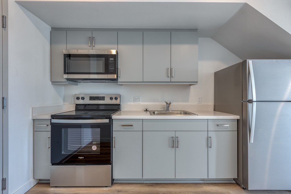 A modern kitchen with a stainless steel refrigerator, microwave, oven, and cabinets.