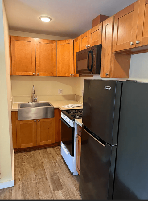 A kitchen with wooden cabinets and a black refrigerator.