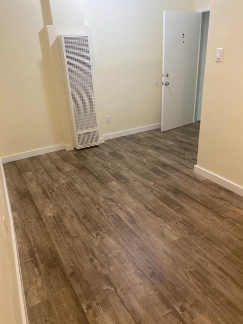 A room with a white door and a wood floor.