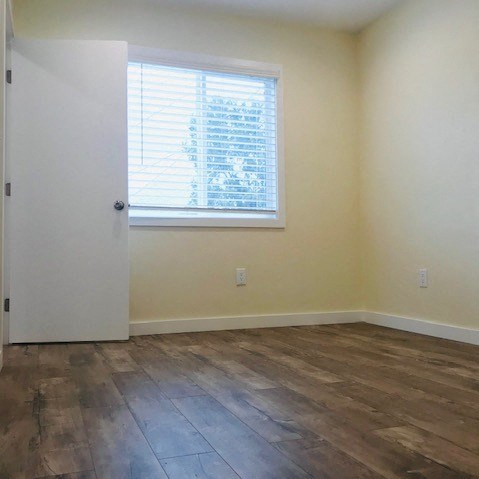 A room with a wooden floor and a window with blinds.