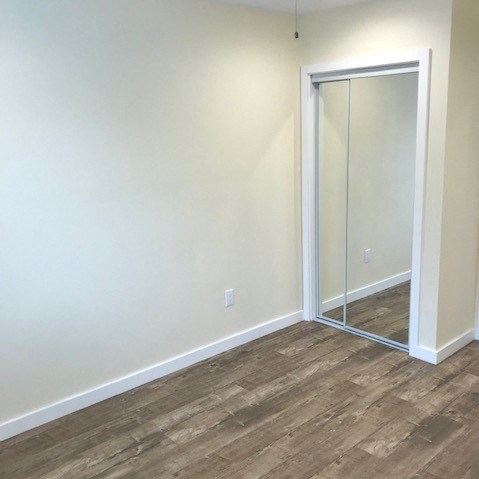 A room with a white door and wood flooring.