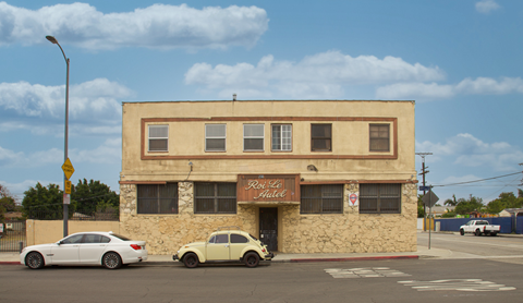 A white car is parked in front of a building with a sign that says "Rose Place".