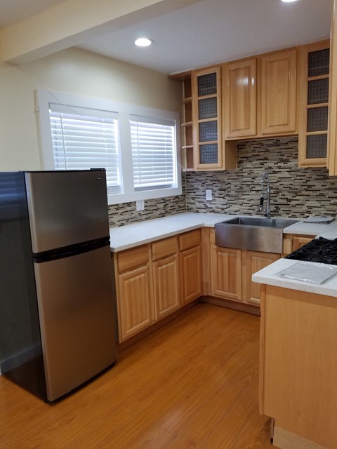 A kitchen with wooden cabinets and a black fridge.