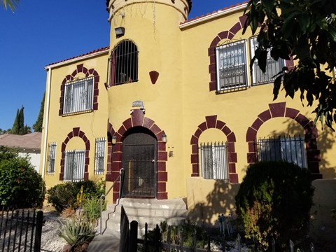 A yellow house with a black gate in front.