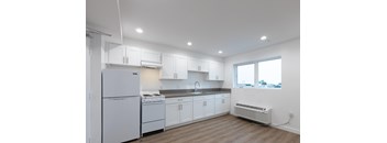 A white kitchen with wood floors and white appliances.