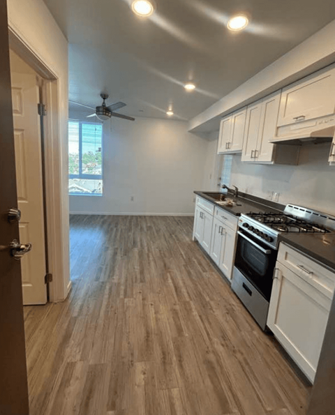 A kitchen with white cabinets and a wooden floor.