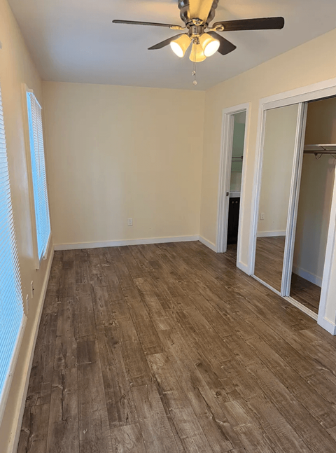 A room with a ceiling fan and wooden flooring.