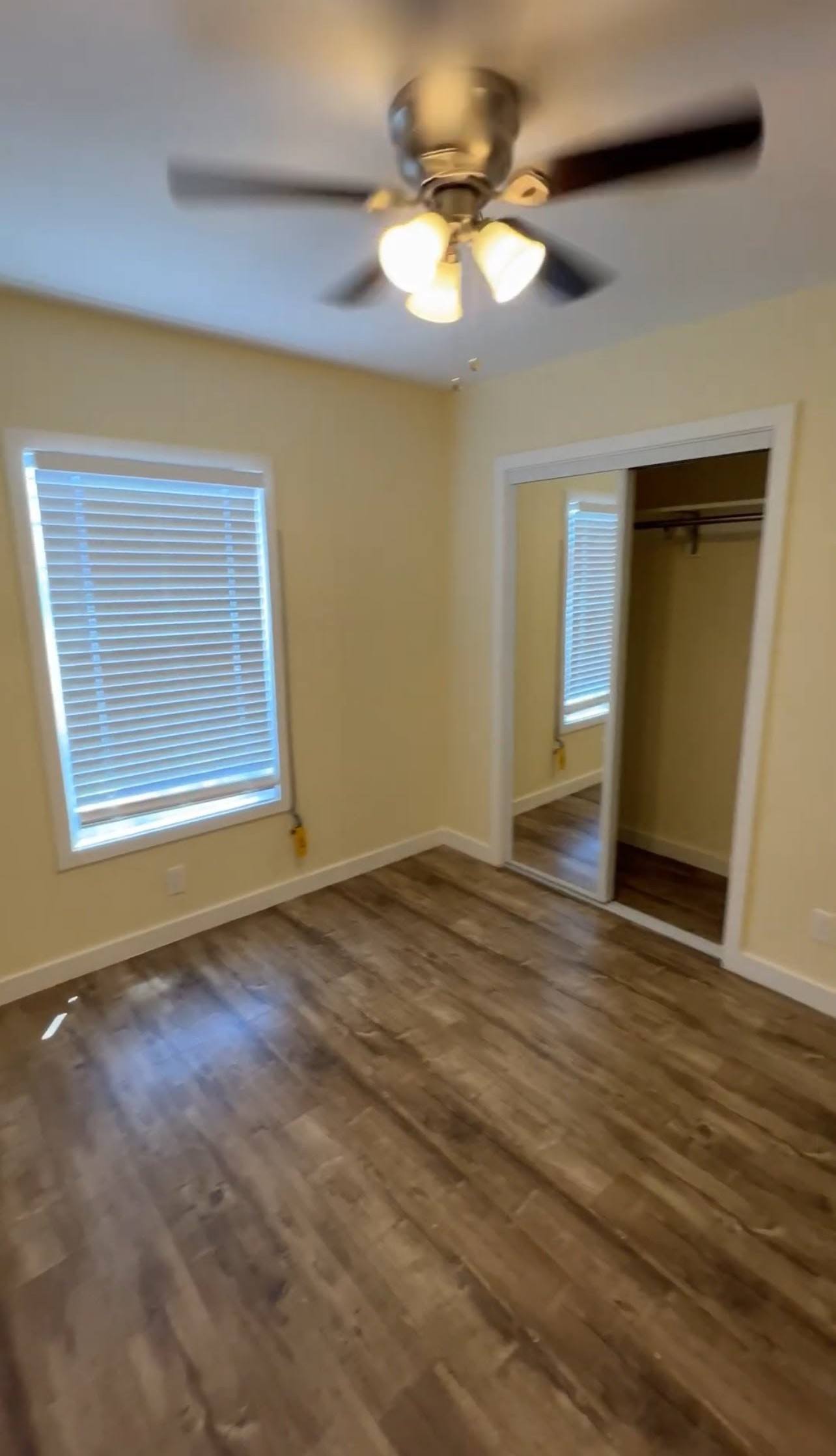 A room with a ceiling fan and a window with blinds.