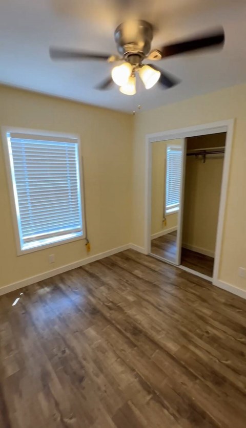 A room with a ceiling fan and a window with blinds.