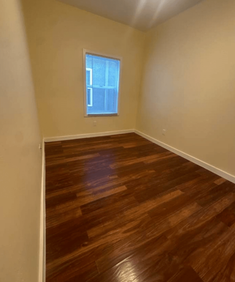 A room with wooden flooring and a window.