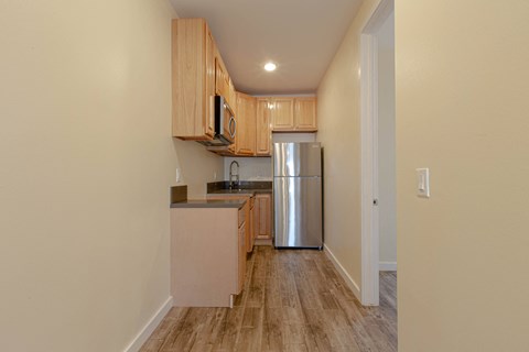 A kitchen with wooden cabinets and a stainless steel refrigerator.