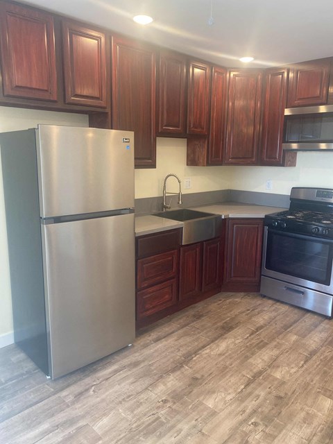 A kitchen with a stainless steel refrigerator and wooden cabinets.