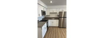A kitchen with white cabinets and a stainless steel refrigerator.