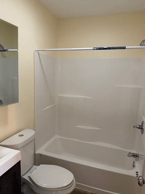 A white toilet sits next to a white bathtub in a bathroom.