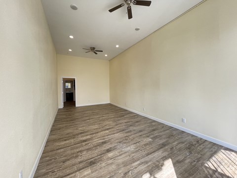 A room with a ceiling fan and wooden flooring.