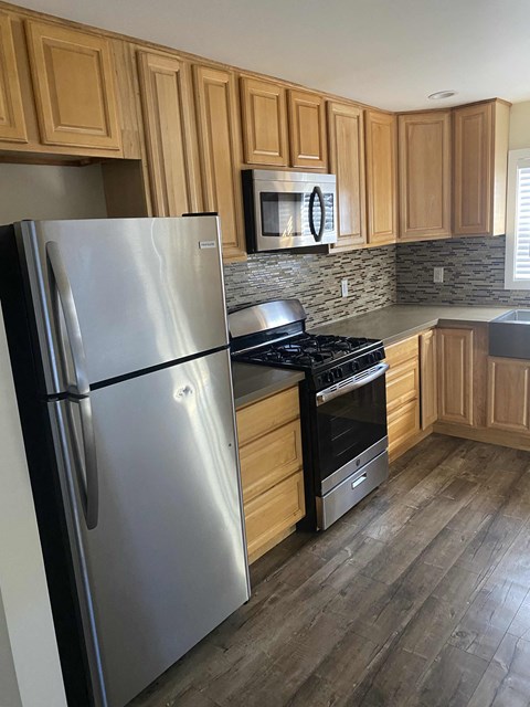 A kitchen with a stainless steel refrigerator and wooden cabinets.