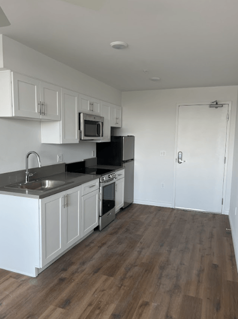 A kitchen with white cabinets and a black stove top oven.