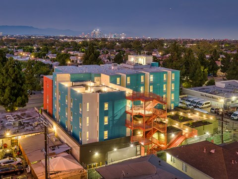 A multi-story building with a mix of blue and orange hues stands out against the cityscape at dusk.