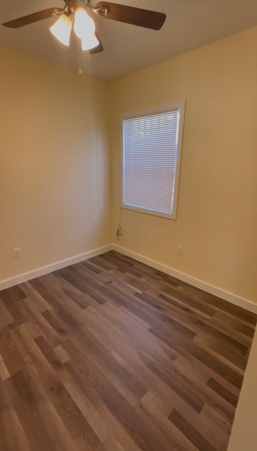 A room with wooden flooring and a ceiling fan.