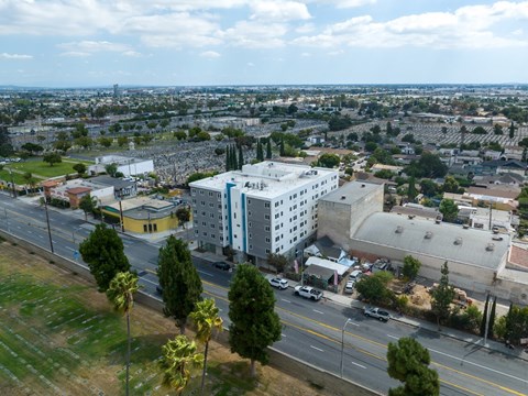A white building with a blue stripe is in the center of a city street.