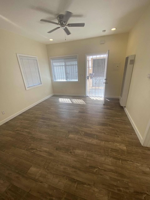 A room with a ceiling fan and wooden flooring.