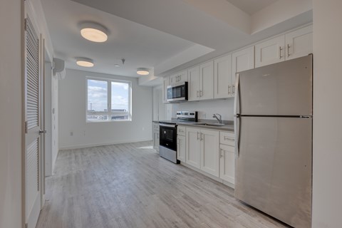 A kitchen with white cabinets and a refrigerator.