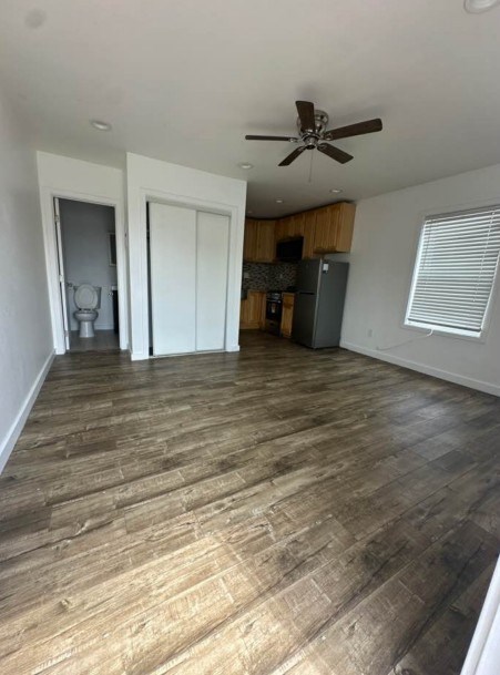 A room with a ceiling fan and wooden flooring.