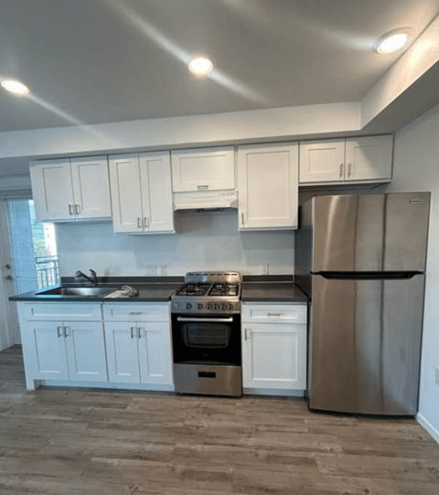 A kitchen with white cabinets and a stainless steel refrigerator.