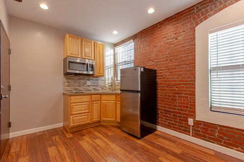 A kitchen with wooden cabinets and a brick wall.