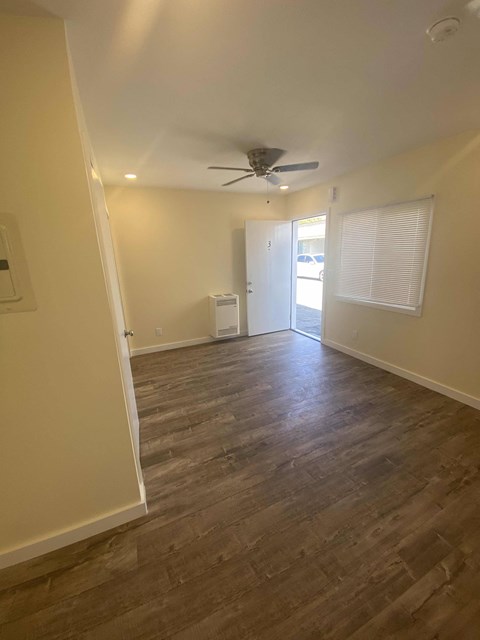 A room with a ceiling fan and wooden flooring.