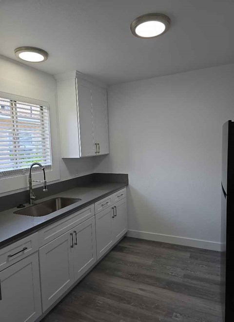 A kitchen with white cabinets and a sink under a window.