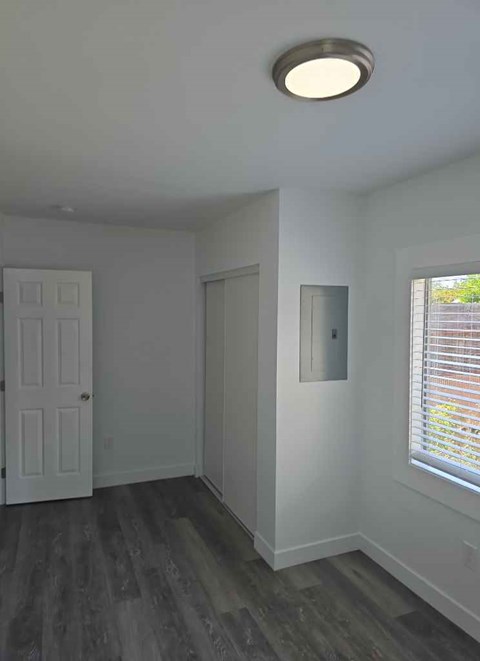 A room with a white door and a window with blinds.