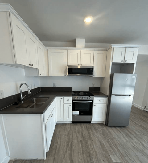 A kitchen with white cabinets and a black countertop.