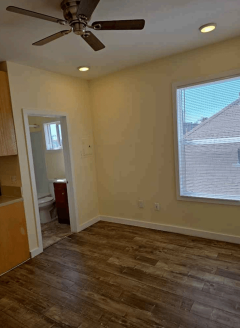 A room with a ceiling fan and a window with blinds.