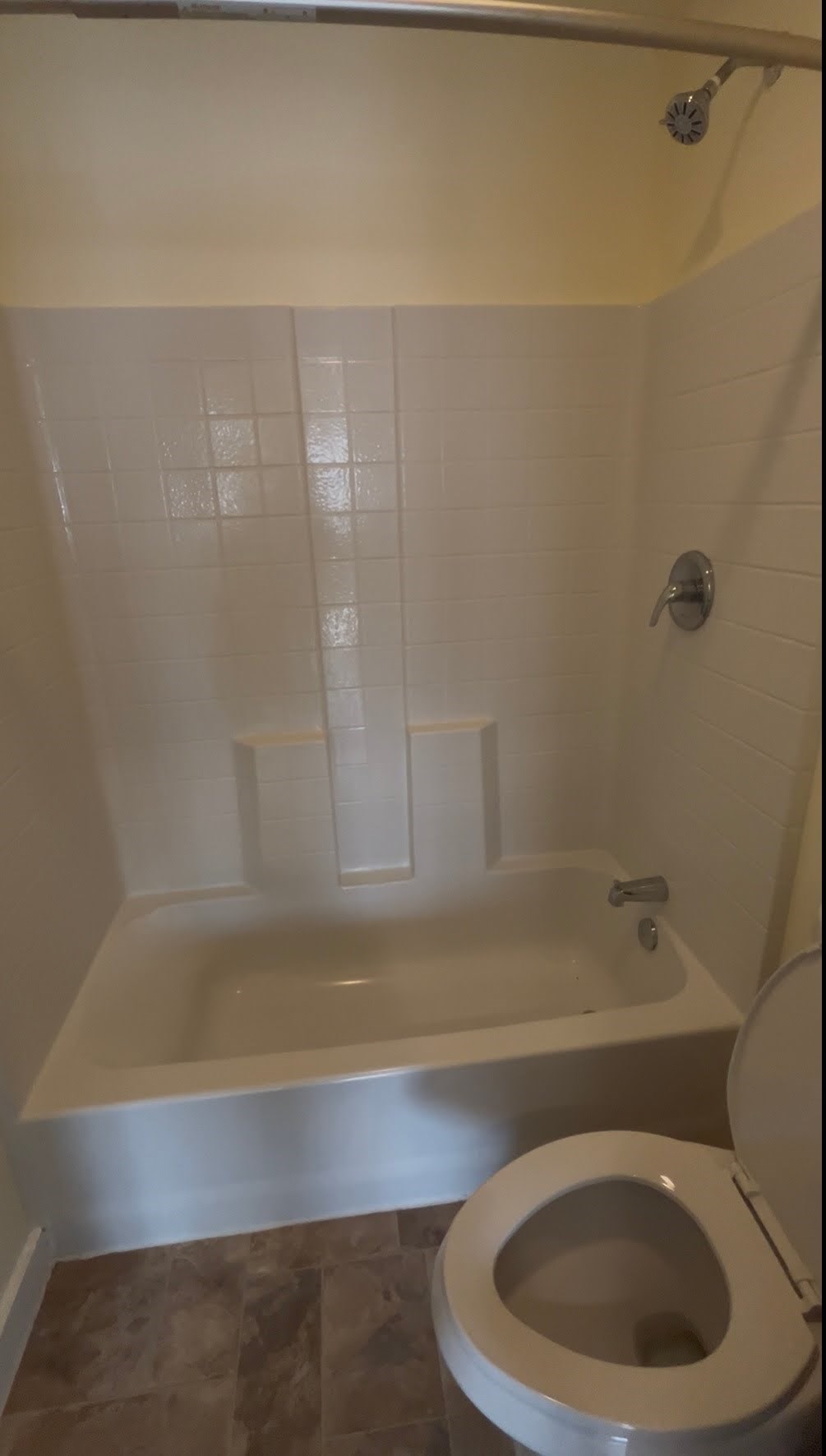 A white toilet sits next to a bathtub in a bathroom.