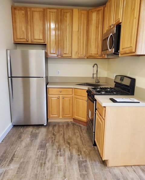 A kitchen with wooden cabinets and a stainless steel refrigerator.
