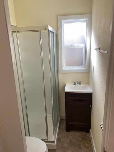 A small bathroom with a toilet, sink, and shower.